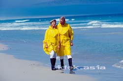 黄色いカッパを着て砂浜を散歩する初老夫婦